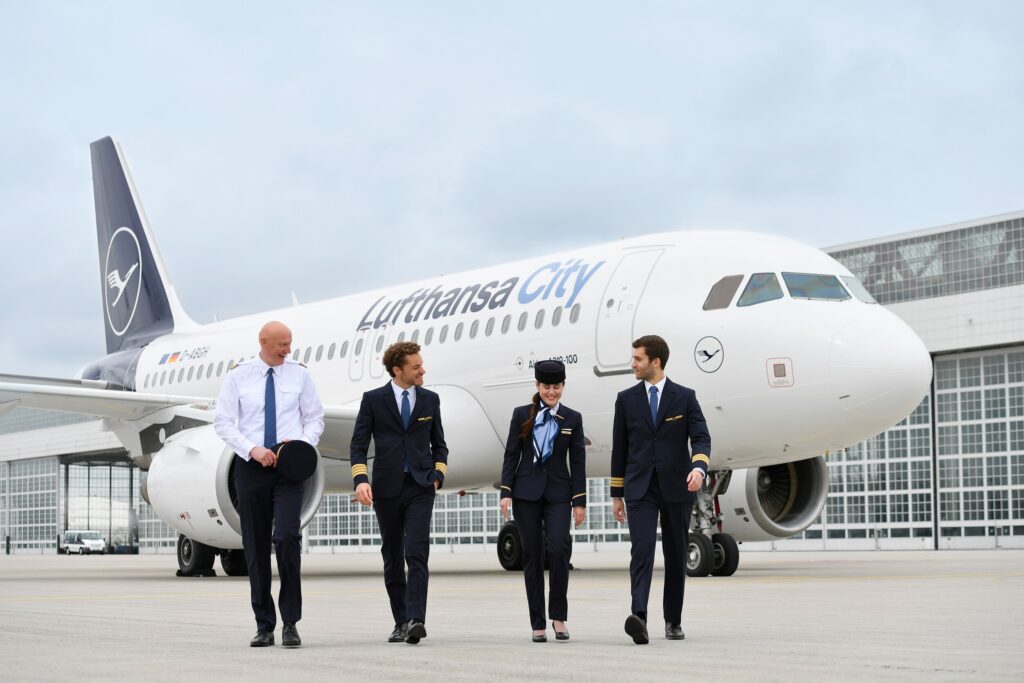 A selection of employees in front of a Lufthansa City plane.